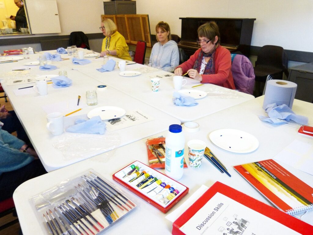 People working at a large table in Alma's craft class.